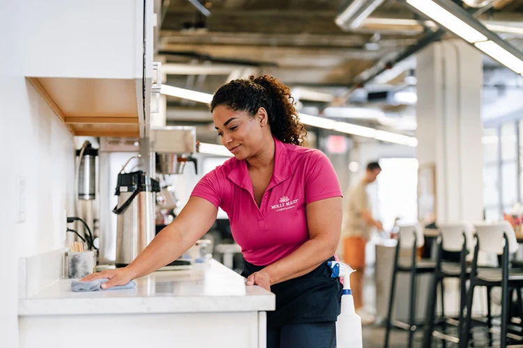 A Molly Maid professional wiping a counter during a commercial recurring cleaning appointment 