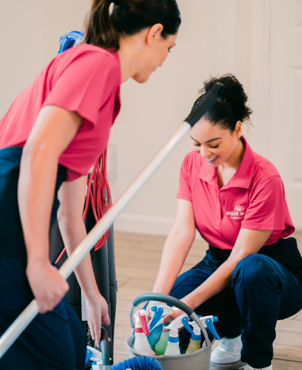 Two Molly Maid professionals cleaning the entryway of a home.