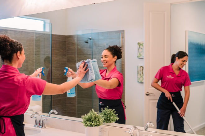 Two Molly Maid professionals cleaning a bathroom. 