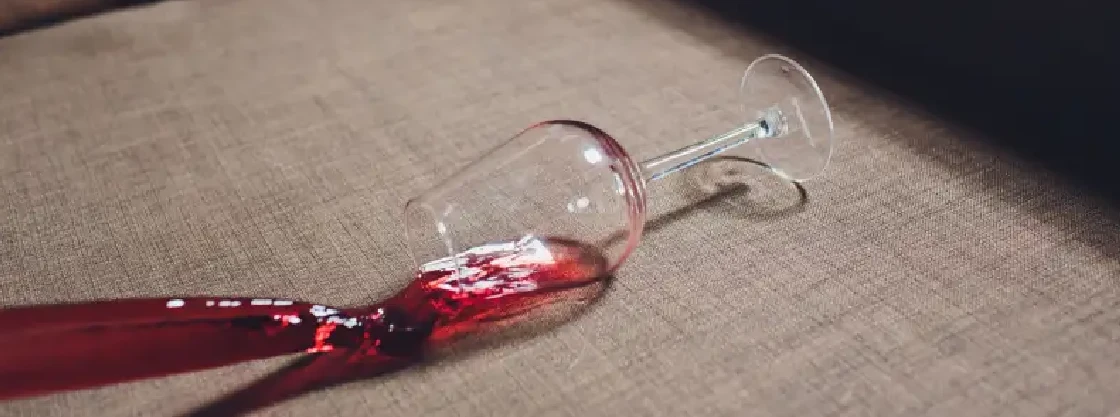 Wine glass spilling on couch.