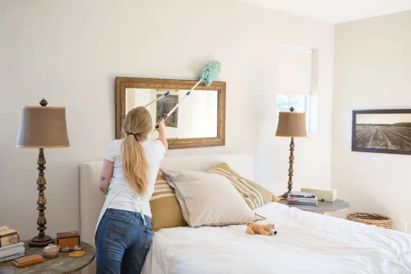 Woman dusting her bedroom.