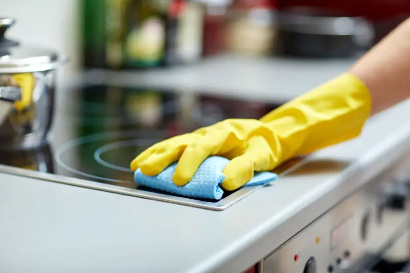 Person cleaning a stove.