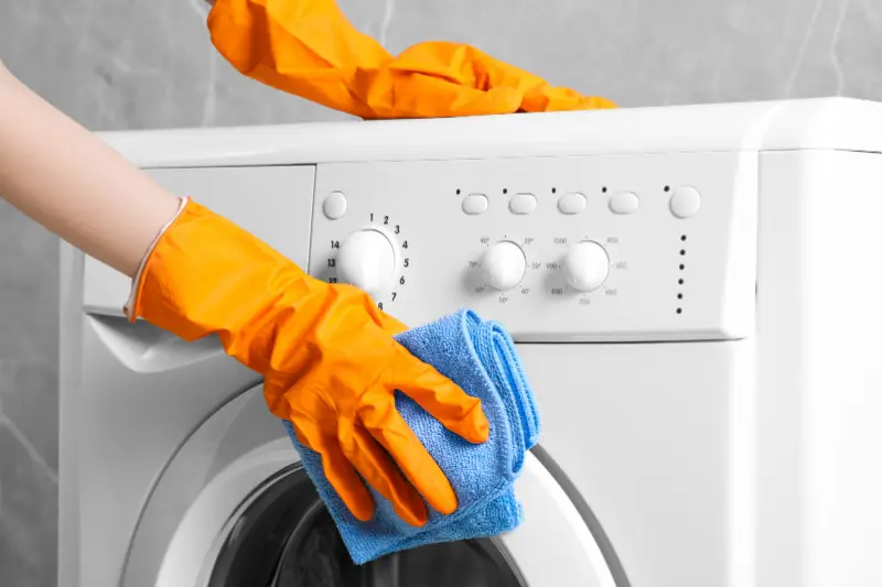 Person cleaning the outside of a washing machine.