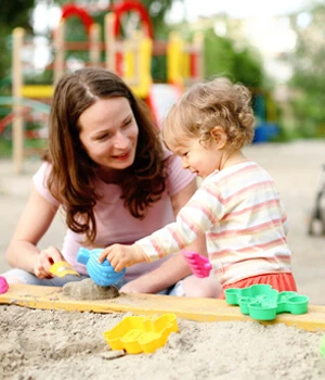 mom and child playing in the sand.