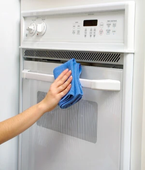 Molly Maid team member cleaning an oven.