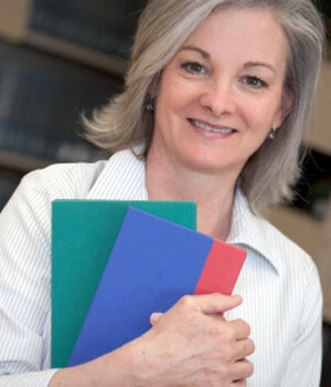 woman smiling holding a notebook.