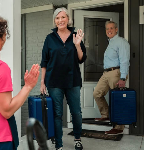 Couple leaving their home with suitcases.