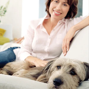 Woman sitting on couch with her dog.