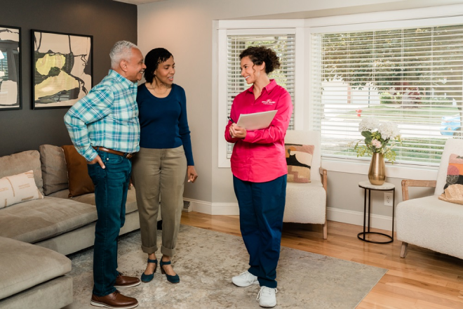 Molly Maid professional reviewing custom cleaning plan with two customers.