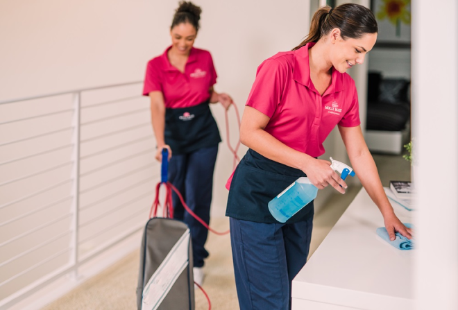 Molly Maid professionals cleaning the hallway of a home.