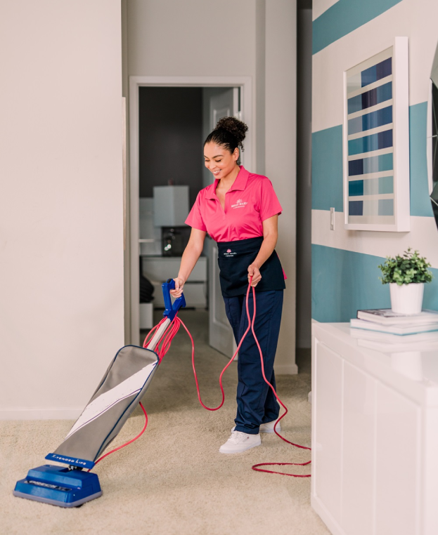 Molly Maid professional vacuuming a hallway in a home.