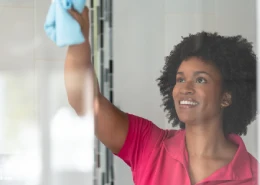 Molly Maid employee cleaning shower glass.