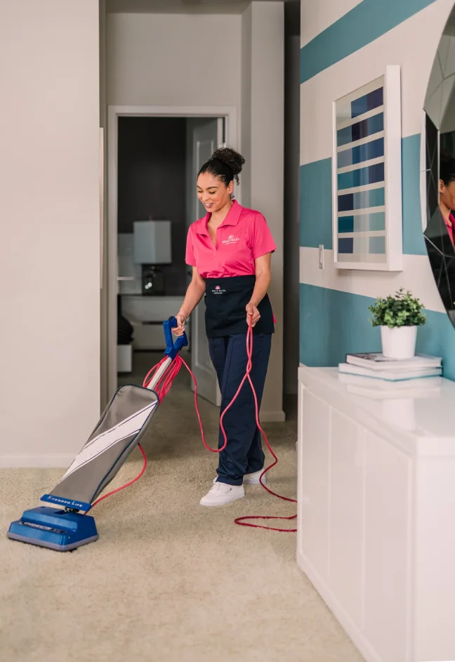 Molly Maid cleaning professional vacuuming a hallway in a home. 