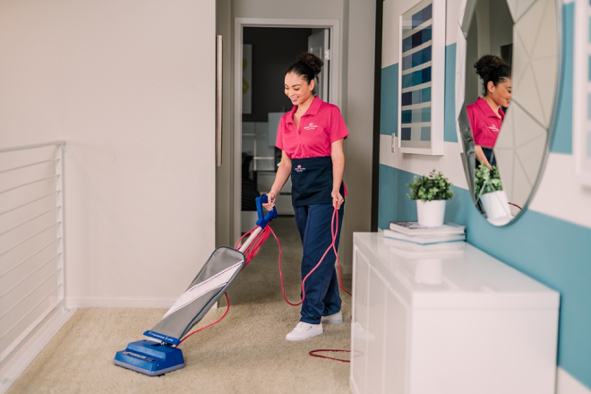 Molly Maid cleaning professional vacuuming a hallway.