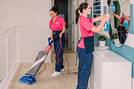 Two Molly Maids dusting a home.