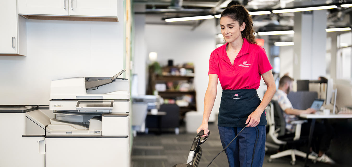 Molly Maid vacuuming the floor in a commercial building.