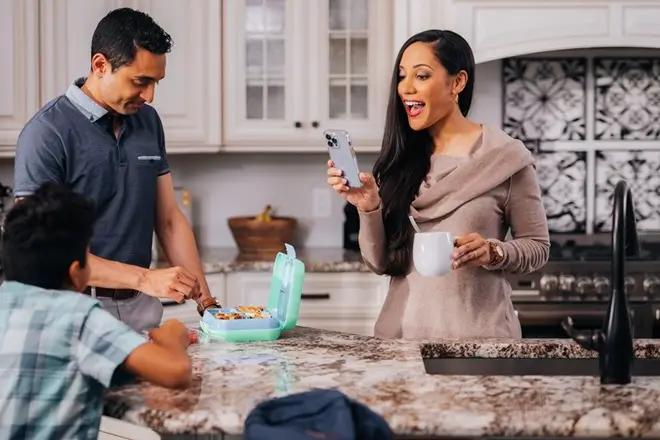 Molly Maid customer booking an appointment on her phone in her kitchen.