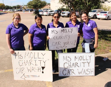 Molly Maid employees holding car wash signs.