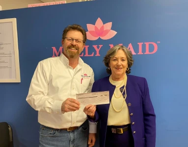 Two people holding a check in front of a Molly Maid logo backdrop.