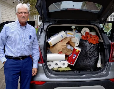 man standing next to a van load of donated toiletries.