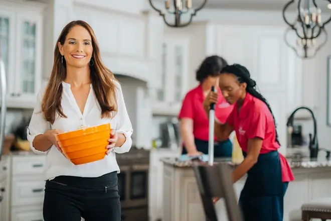 Customer smiling while Molly Maid professionals cleaning a kitchen.