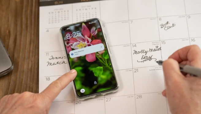 Cell phone with a calendar in the background that shows a Molly Maid appointment.