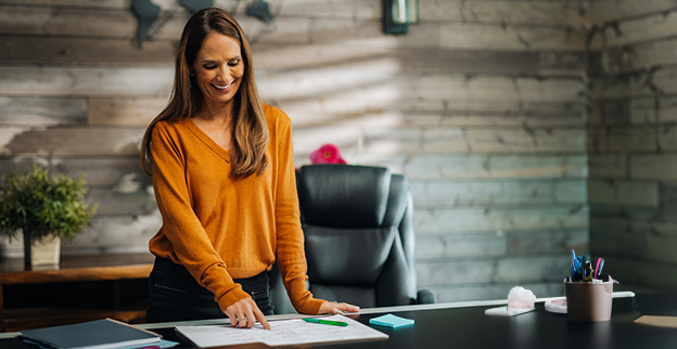 Happy woman pointing to a date on her desk calendar.