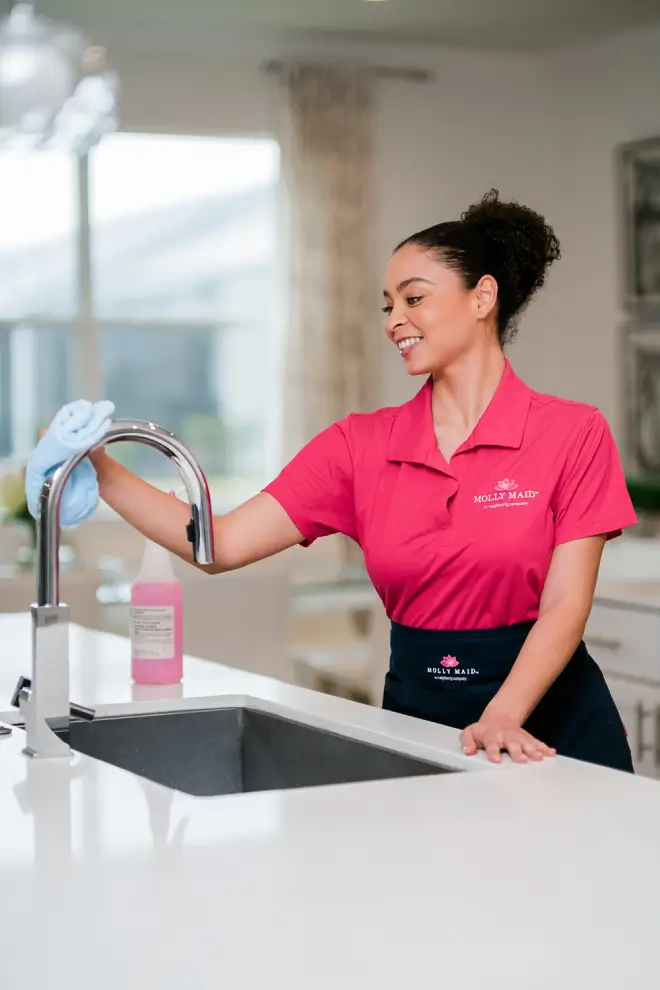 Molly Maid service professional cleaning a kitchen sink. 