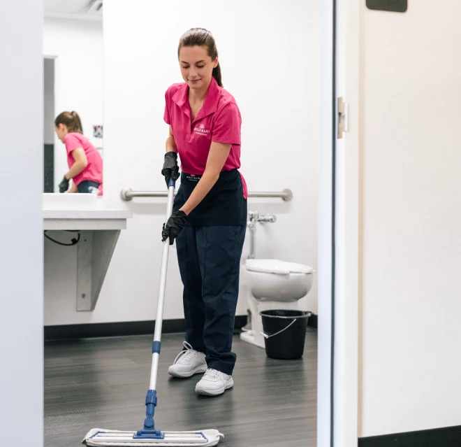 Molly Maid mopping a bathroom floor at a business.