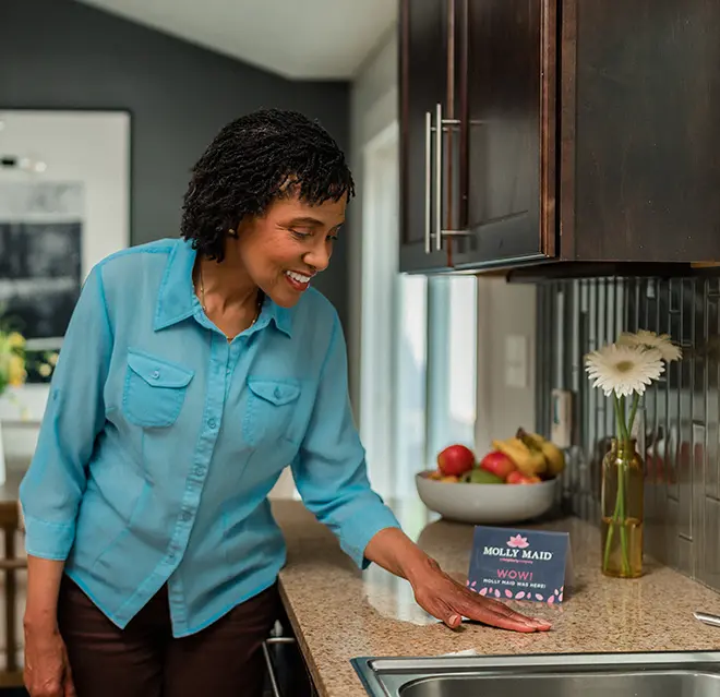 Happy Molly Maid customer standing in her kitchen.