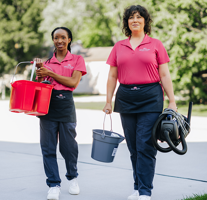 Two smiling Molly Maid employees walking up to a customer's home.