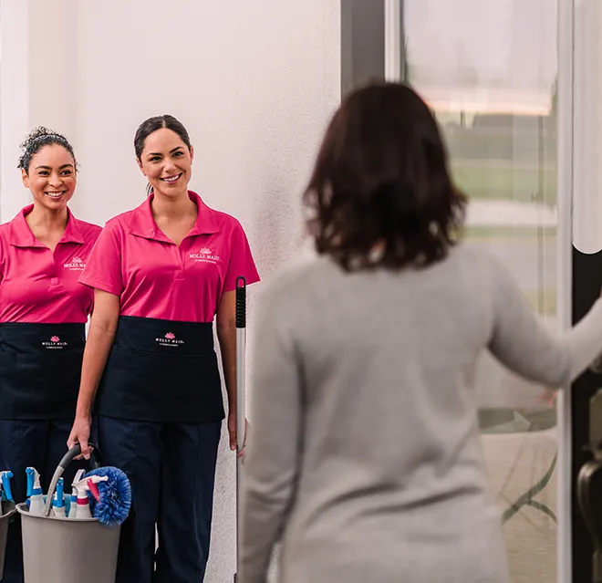 Molly Maid customer greeting two maids at her door.