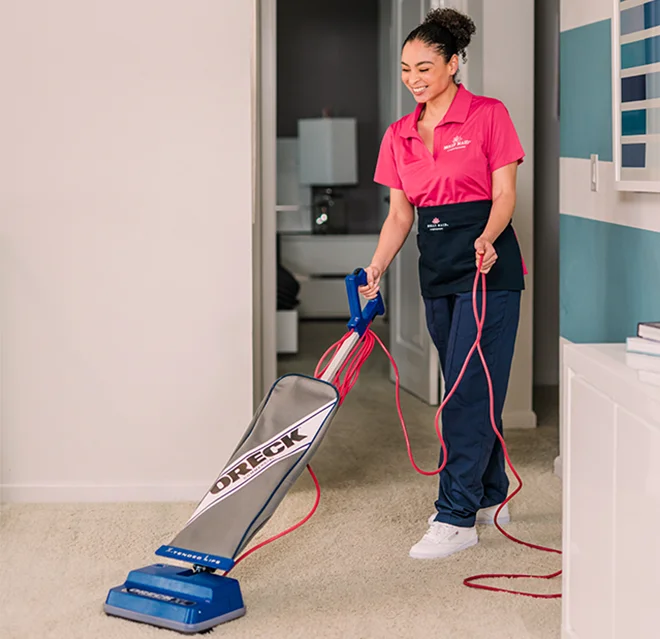 Smiling Molly Maid vaccuming a floor.