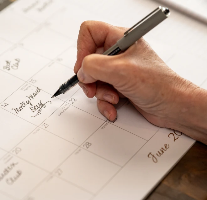 Customer writing Molly Maid appointment on a calendar.