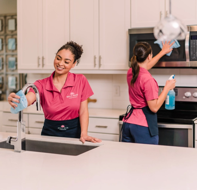 Two Molly Maid maids cleaning a kitchen together.