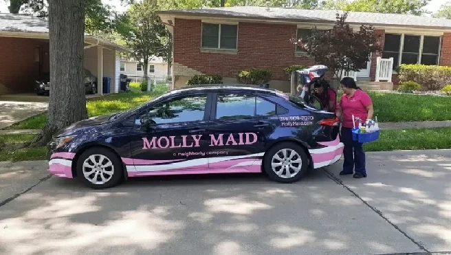 Molly Maid professionals in St. Louis unloading supplies from a company car before house cleaning service.