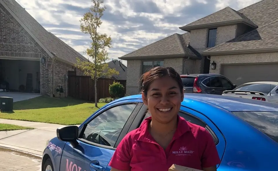 Molly Maid professional smiling outside of house in Flower Mound, TX.