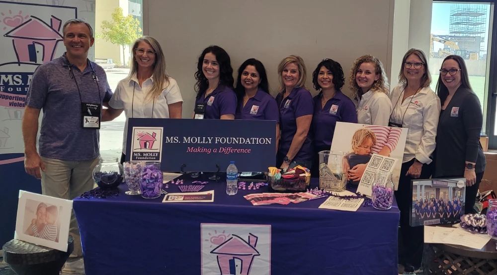 Group of Molly Maid employees behind a Ms. Molly Foundation booth.