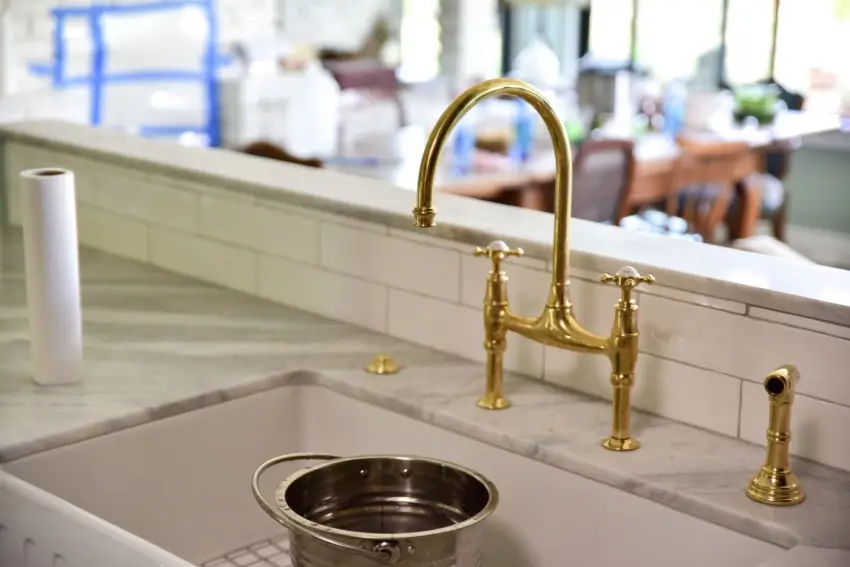Kitchen sink with brass faucet and handles.