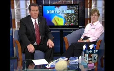 Two local ABC News anchors sitting in blue chairs on news set in front of TV screen that says 