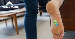 A person lifting up their foot, with cereal and other debris stuck to the bottom