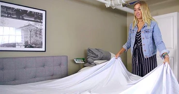 woman putting sheets on a bed