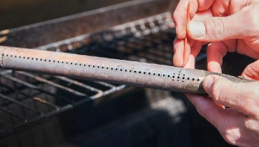 Person cleaning a propane grill