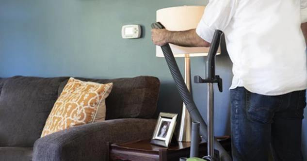 Person using handheld vacuum to clean lampshade