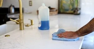 hand cleaning quartz countertop with blue towel