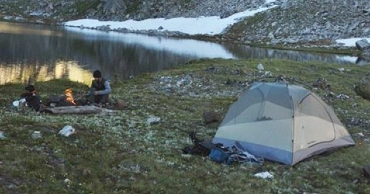 Campsite with tent and camp fire on lake