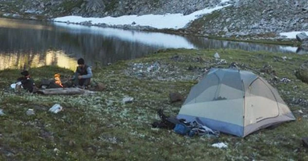 Campsite with tent and campfire on lake