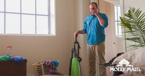 Man drinking out of a mug while looking at a messy bedroom