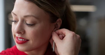 woman placing earring in ear