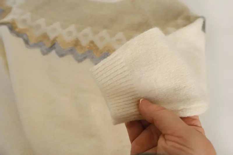 Close up image of hand holding a sweater sleeve.